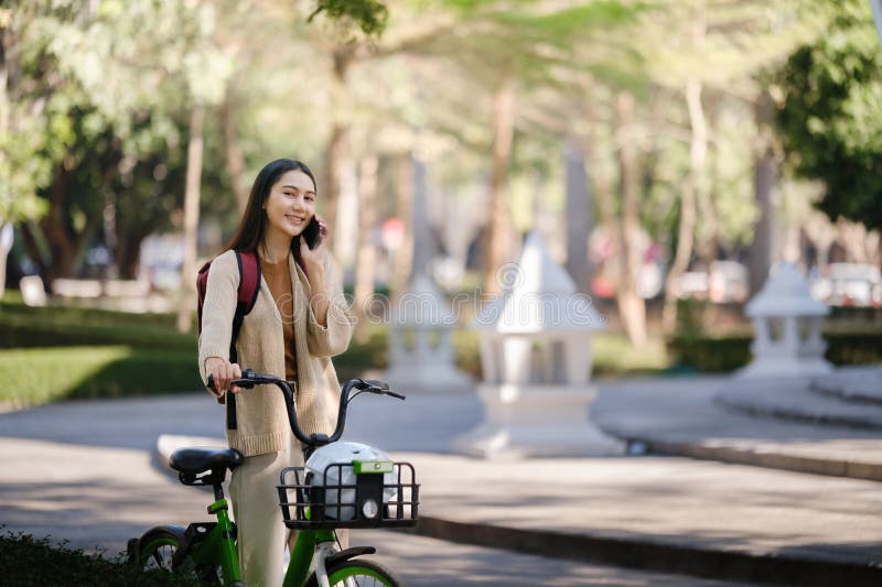 Bella donna che fa una passeggiata in bicicletta nel parco con una donna che tiene in mano uno smartphone con una donna affittuari immagini stock libere da diritti