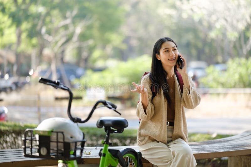 Bella donna che fa una passeggiata in bicicletta nel parco con una donna che tiene in mano uno smartphone con una donna affittuari fotografie stock libere da diritti