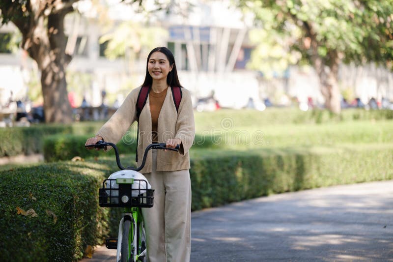 Bella donna che fa una passeggiata in bicicletta nel parco con una donna che tiene in mano uno smartphone con una donna affittuari immagine stock libera da diritti