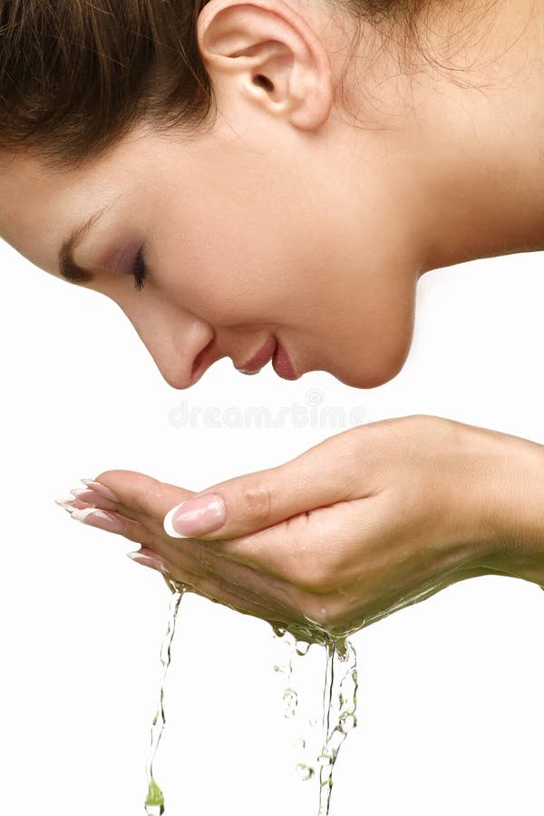 Beautiful woman refreshing her face with water on white. Beautiful woman refreshing her face with water on white