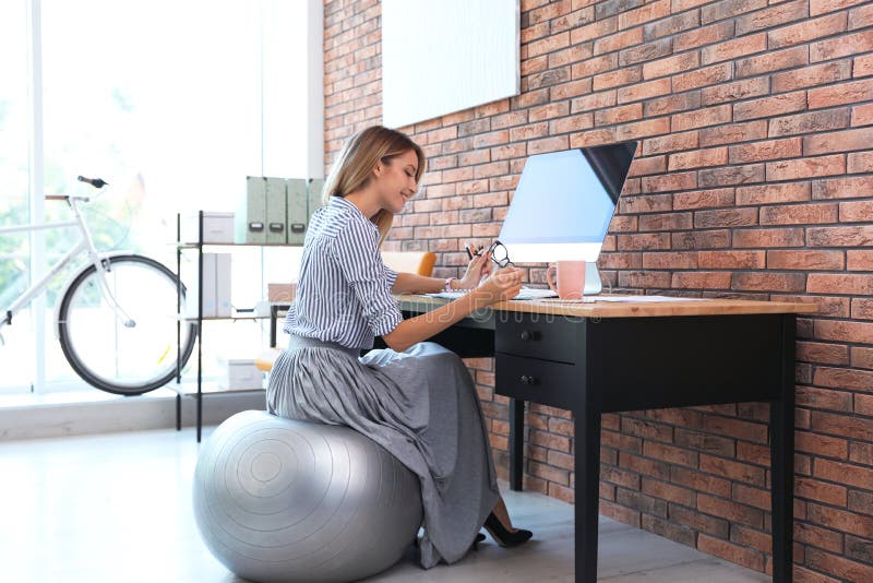 Bella donna di affari che si siede sulla palla di forma fisica fotografie stock Bella donna di affari che si siede sulla palla di forma fisica fotografie stock
