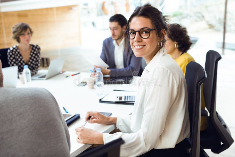 Bella donna di affari elegante che lavora con il computer portatile mentre esaminando macchina fotografica sul posto coworking fotografia stock Bella donna di affari elegante che lavora con il computer portatile mentre esaminando macchina fotografica sul posto coworking fotografia stock