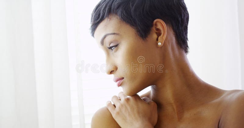 Bella donna di colore topless che si abbraccia e che guarda fuori finestra immagini stock Bella donna di colore topless che si abbraccia e che guarda fuori finestra immagini stock
