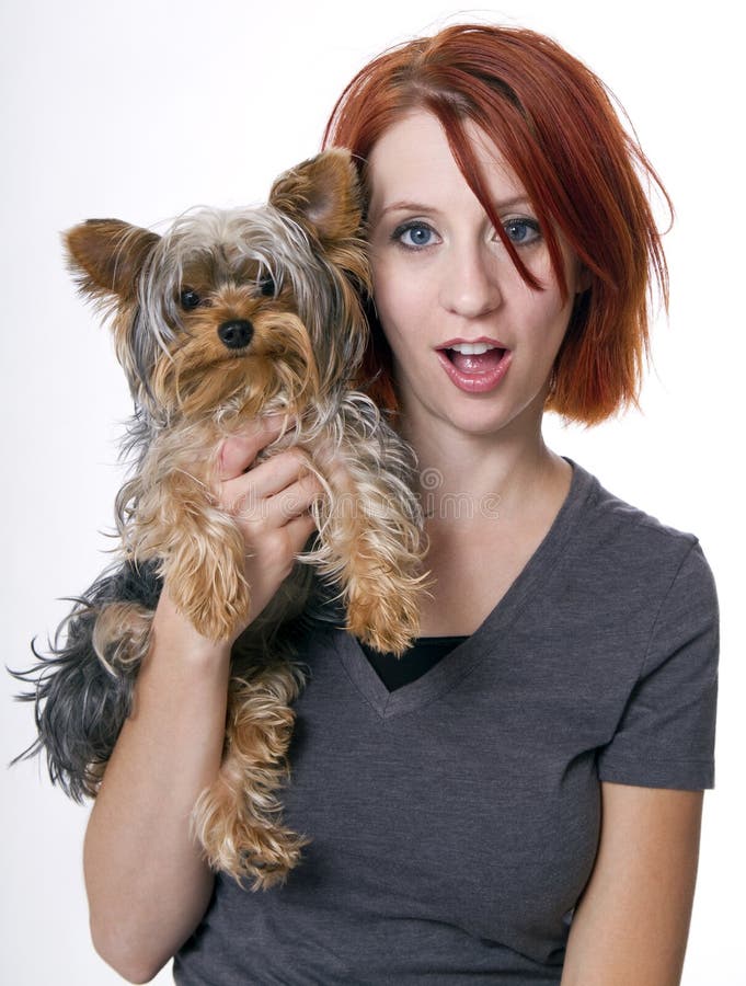 Redheaded young woman holding her cute and friendly pet dog. Redheaded young woman holding her cute and friendly pet dog