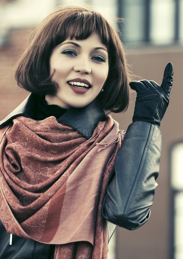 Bella donna felice di modo in cappotto di cuoio che cammina in via della città fotografie stock libere da diritti Bella donna felice di modo in cappotto di cuoio che cammina in via della città fotografie stock libere da diritti
