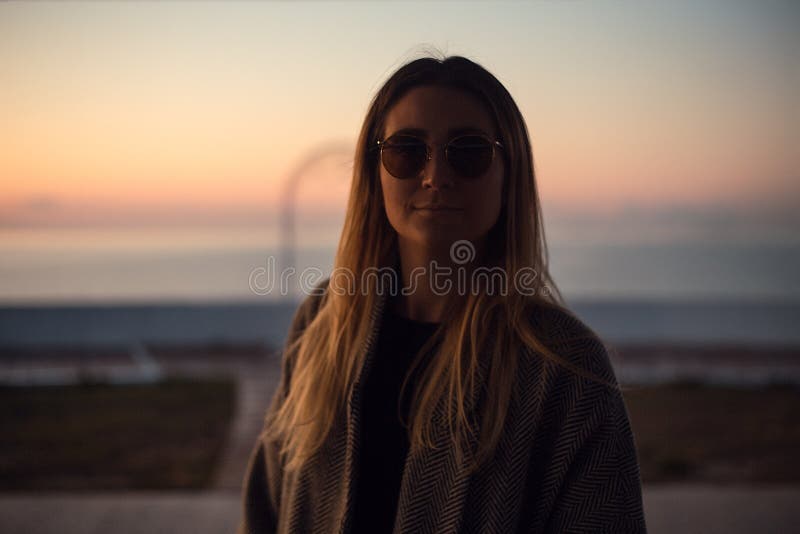 Bella donna felice in occhiali da sole che stanno al mare, ragazza in cappotto grigio fotografie stock Bella donna felice in occhiali da sole che stanno al mare, ragazza in cappotto grigio fotografie stock