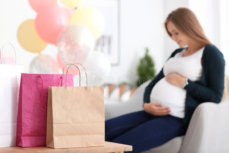 Bella donna incinta con i regali per il partito di doccia del bambino a casa immagini stock Bella donna incinta con i regali per il partito di doccia del bambino a casa immagini stock