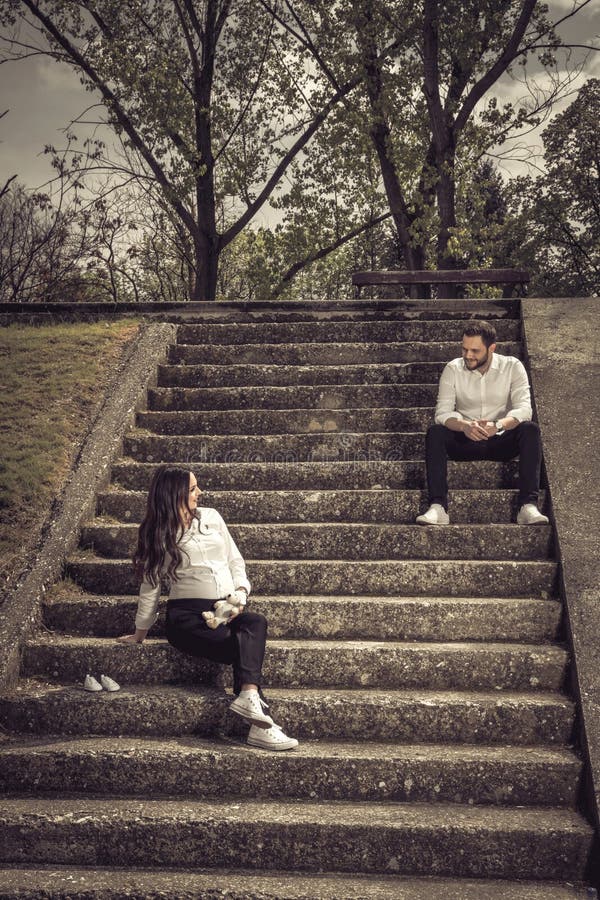 Bella donna incinta e suo il marito che si siedono sull'le scale di pietra fotografie stock libere da diritti Bella donna incinta e suo il marito che si siedono sull'le scale di pietra fotografie stock libere da diritti
