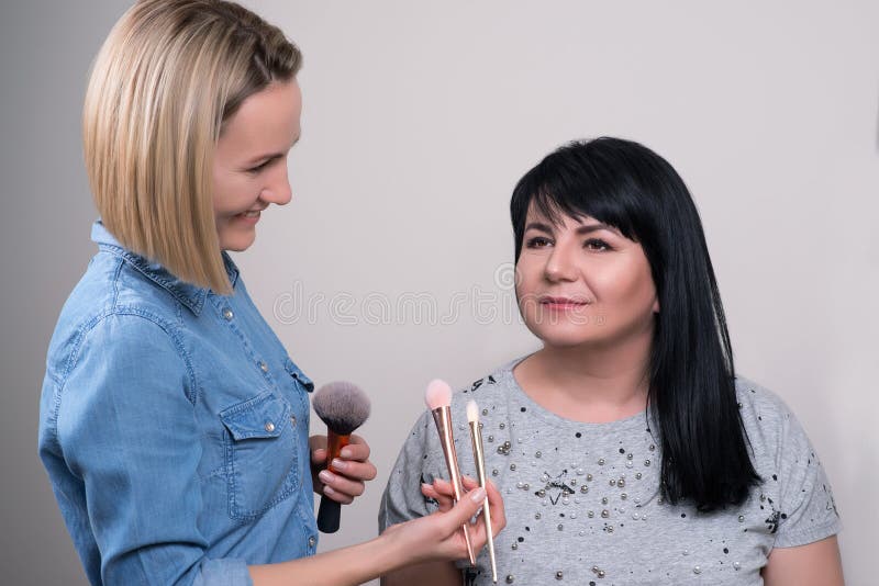 Bella donna matura al salone di bellezza Truccatore che fa trucco per la donna affascinante La donna senior felice con il profess fotografie stock Bella donna matura al salone di bellezza Truccatore che fa trucco per la donna affascinante La donna senior felice con il profess fotografie stock