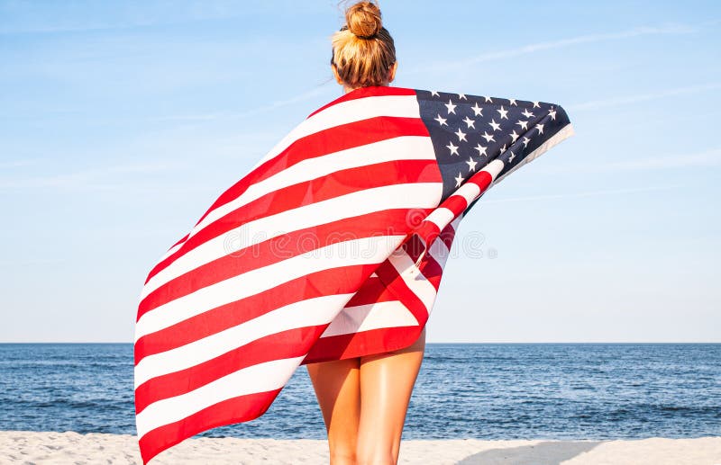 Bella donna patriottica con la bandiera americana sulla spiaggia Festa dell'indipendenza di U.S.A., il 4 luglio Concetto di liber fotografia stock Bella donna patriottica con la bandiera americana sulla spiaggia Festa dell'indipendenza di U.S.A., il 4 luglio Concetto di liber fotografia stock