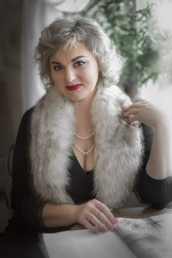 Bella donna seduta accanto alla finestra a un tavolo in una caffetteria con una rivista Cosplay fotografia stock Bella donna seduta accanto alla finestra a un tavolo in una caffetteria con una rivista Cosplay fotografia stock