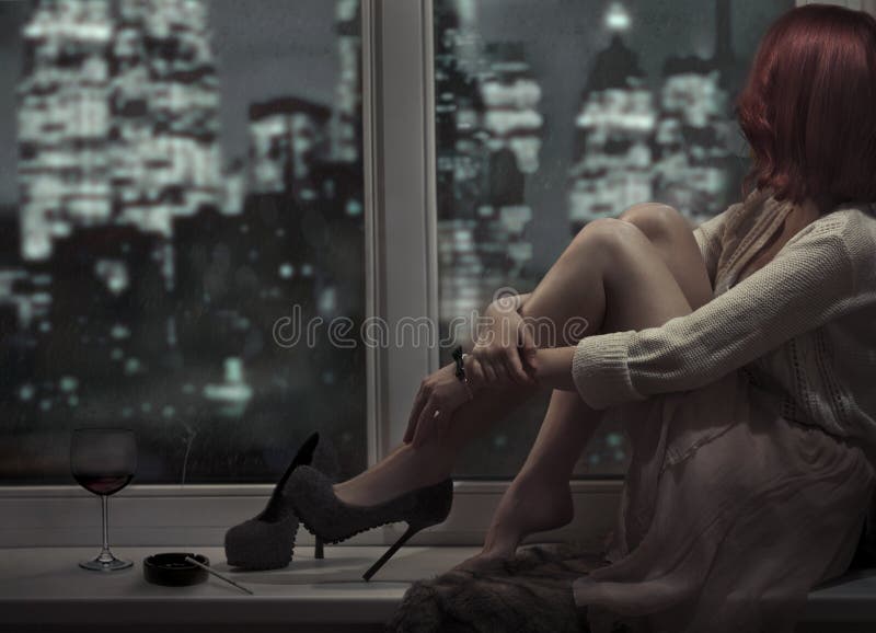 Bella donna sola che si siede sulla finestra