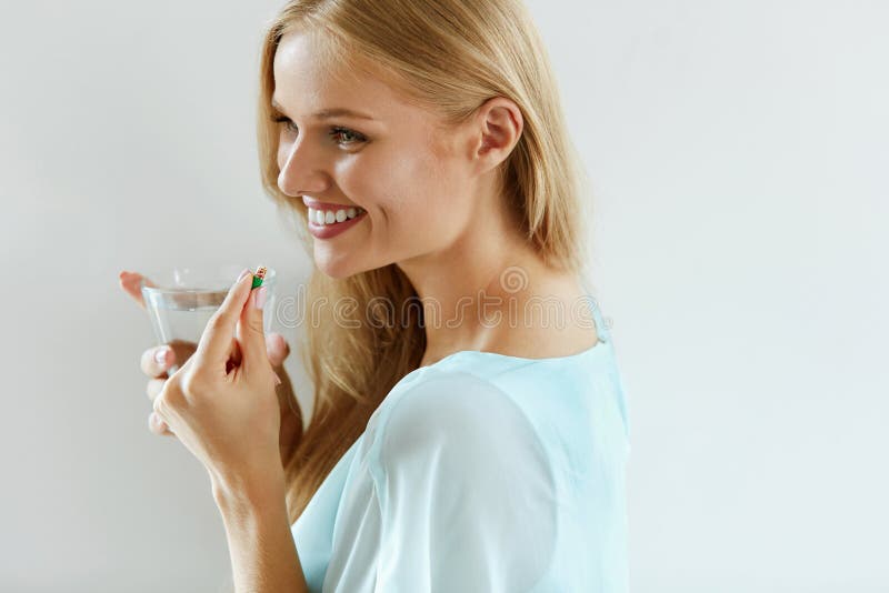 Bella donna sorridente che prende la pillola della vitamina Supplemento dietetico immagini stock Bella donna sorridente che prende la pillola della vitamina Supplemento dietetico immagini stock