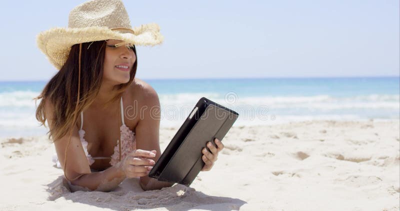Bella donna sul cappello di paglia d'uso della spiaggia