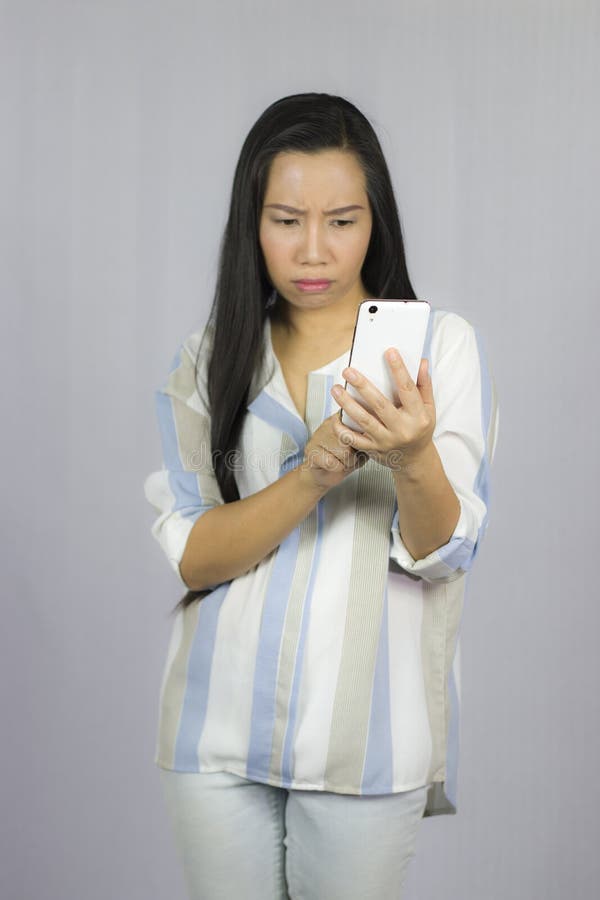 Bella donna sveglia in camicia che agisce giocante sul telefono Isolato su priorit? bassa grigia immagini stock libere da diritti Bella donna sveglia in camicia che agisce giocante sul telefono Isolato su priorit? bassa grigia immagini stock libere da diritti