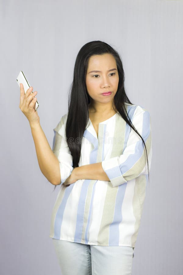 Bella donna sveglia in camicia che agisce giocante sul telefono Isolato su priorit? bassa grigia fotografia stock libera da diritti Bella donna sveglia in camicia che agisce giocante sul telefono Isolato su priorit? bassa grigia fotografia stock libera da diritti