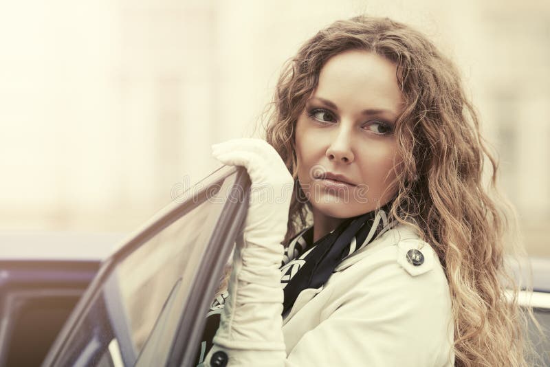 Bella donna triste di modo in trench accanto alla sua automobile fotografia stock libera da diritti Bella donna triste di modo in trench accanto alla sua automobile fotografia stock libera da diritti