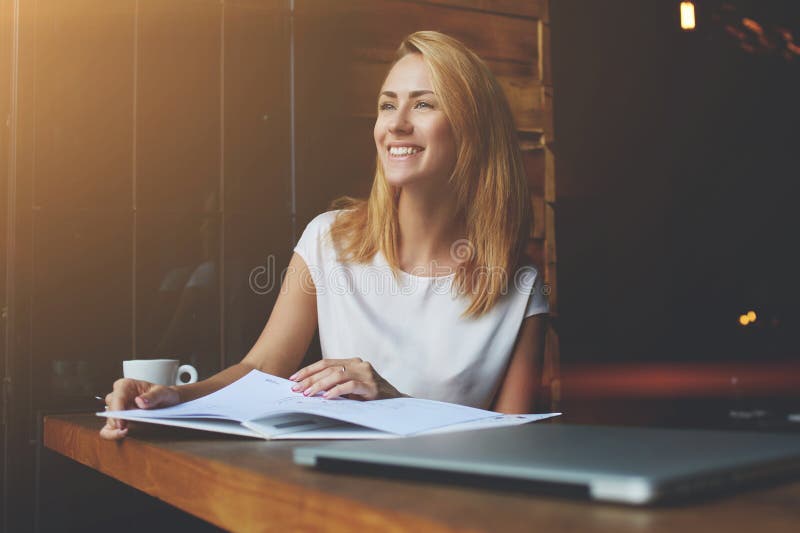 Bella femmina con il sorriso sveglio che distoglie lo sguardo mentre rilassandosi dopo il lavoro sul suo computer portatile immagini stock libere da diritti Bella femmina con il sorriso sveglio che distoglie lo sguardo mentre rilassandosi dopo il lavoro sul suo computer portatile immagini stock libere da diritti