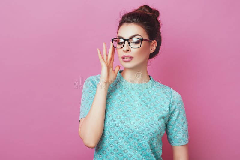 Bella giovane donna adorabile con i vetri commoventi del panino dei capelli su fondo rosa isolato Affare della gente di bellezza immagini stock Bella giovane donna adorabile con i vetri commoventi del panino dei capelli su fondo rosa isolato Affare della gente di bellezza immagini stock