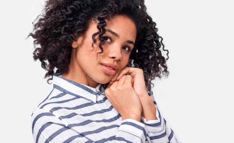 Bella giovane donna africana americana sorridente indossa una camicia a strisce casual che guarda da un lato. femmina di pelle scu fotografia stock