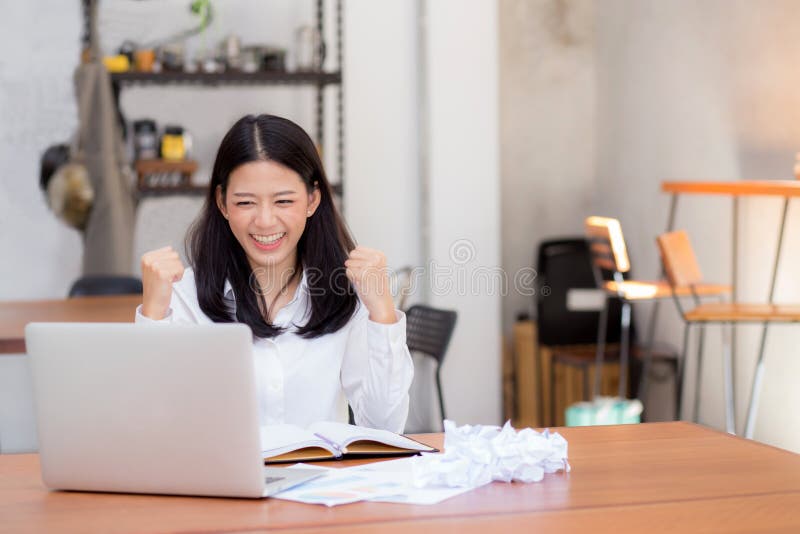 Bella giovane donna asiatica che lavora online sul computer portatile che si siede alla caffetteria fotografie stock libere da diritti Bella giovane donna asiatica che lavora online sul computer portatile che si siede alla caffetteria fotografie stock libere da diritti