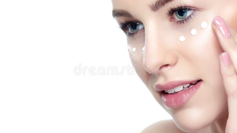 Bella giovane donna bionda che applica la crema di fronte sotto lei occhi Trattamento facciale Cosmetologia, bellezza e concetto