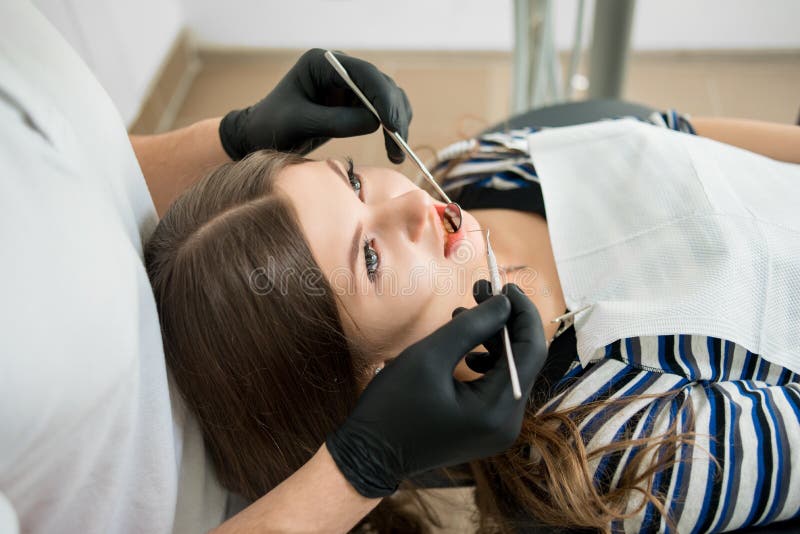 Bella giovane donna che ha controllo dentario su in ufficio dentario Dentista denti d'esame del ` una s del paziente con gli stru fotografia stock Bella giovane donna che ha controllo dentario su in ufficio dentario Dentista denti d'esame del ` una s del paziente con gli stru fotografia stock