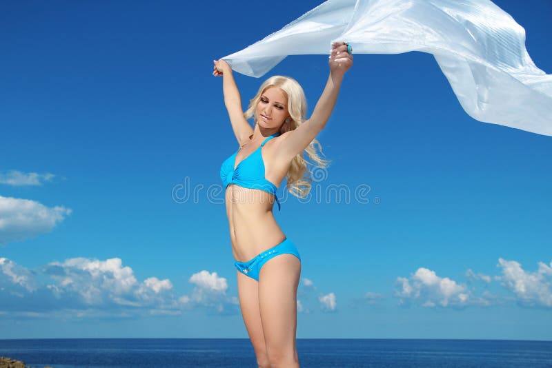 Bella giovane donna che si rilassa sopra il cielo blu con i tiss bianchi immagine stock Bella giovane donna che si rilassa sopra il cielo blu con i tiss bianchi immagine stock