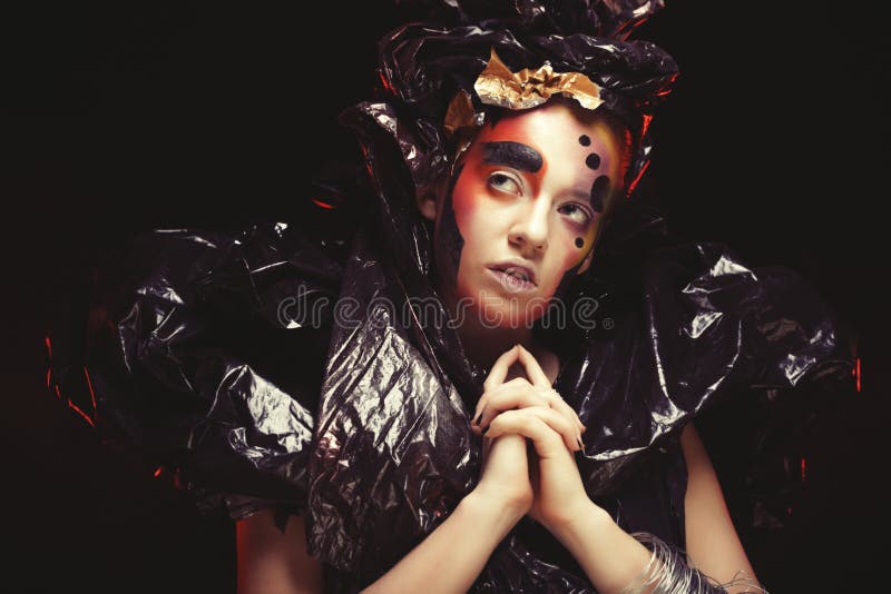 Bella giovane donna con trucco luminoso di fantasia e costume che posa su un fondo nero in nuvole di fumo Halloween immagini stock Bella giovane donna con trucco luminoso di fantasia e costume che posa su un fondo nero in nuvole di fumo Halloween immagini stock