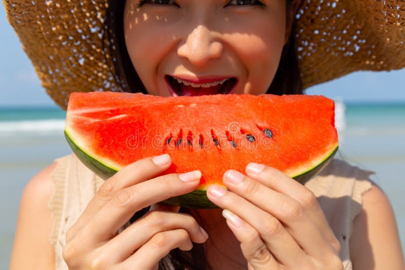 Bella giovane donna incantante che mangia anguria per raffreddare ed estiguere la sua sete nella stagione estiva alla spiaggia Se fotografia stock libera da diritti Bella giovane donna incantante che mangia anguria per raffreddare ed estiguere la sua sete nella stagione estiva alla spiaggia Se fotografia stock libera da diritti
