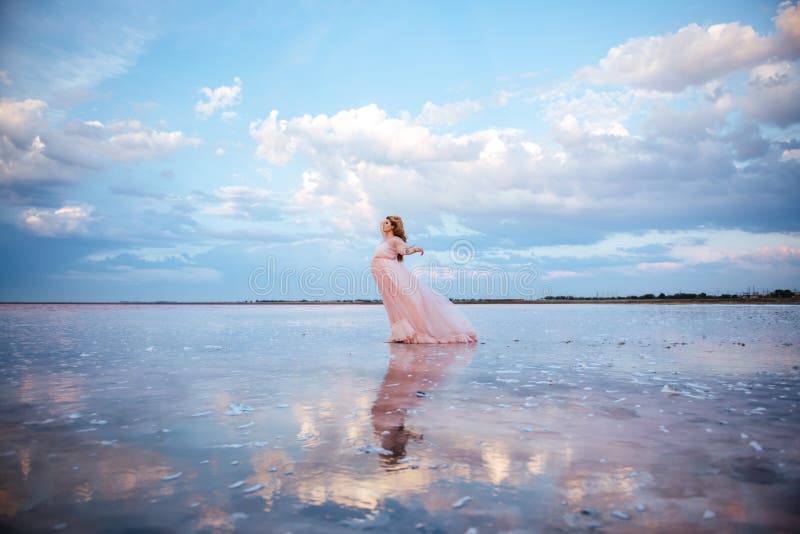 Bella giovane donna incinta che gode del sole sul lago rosa fotografia stock Bella giovane donna incinta che gode del sole sul lago rosa fotografia stock