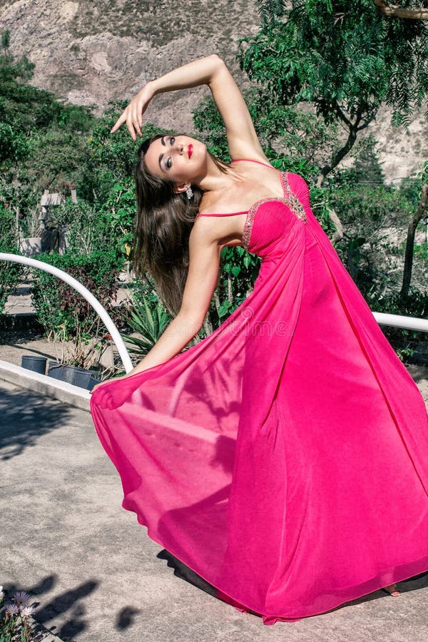 Bella giovane donna in un vestito uguagliante lungo che posa in natura, sviluppante lo immagini stock libere da diritti Bella giovane donna in un vestito uguagliante lungo che posa in natura, sviluppante lo immagini stock libere da diritti