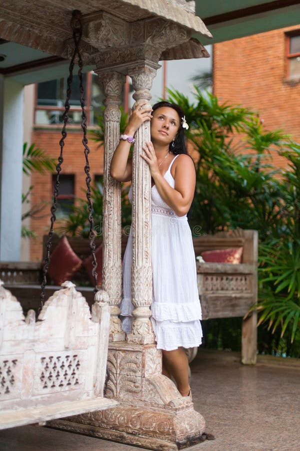 Bella giovane donna in vestito bianco che sogna dell'oscillazione d'annata in giardino Concetto di estate e di viaggio fotografia stock Bella giovane donna in vestito bianco che sogna dell'oscillazione d'annata in giardino Concetto di estate e di viaggio fotografia stock