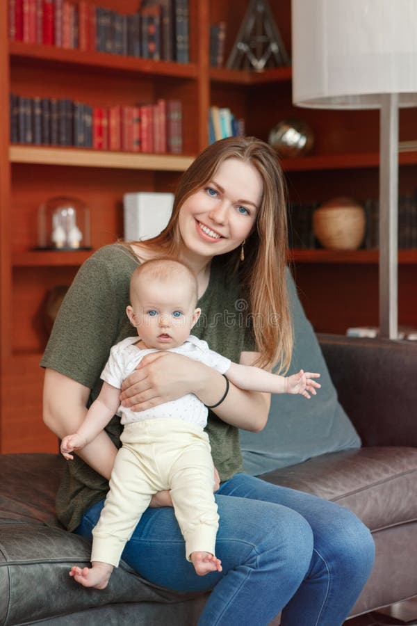 Bella giovane madre caucasica bianca sorridente della donna che tiene il bambino adorabile sveglio della ragazza del neonato immagine stock libera da diritti Bella giovane madre caucasica bianca sorridente della donna che tiene il bambino adorabile sveglio della ragazza del neonato immagine stock libera da diritti