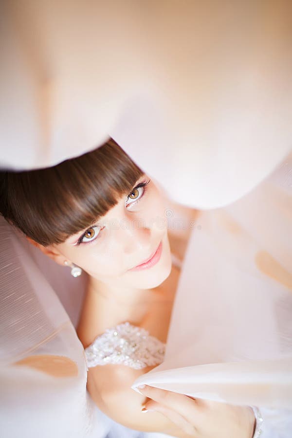 Bella giovane sposa con trucco di nozze e acconciatura in bedro fotografia stock Bella giovane sposa con trucco di nozze e acconciatura in bedro fotografia stock