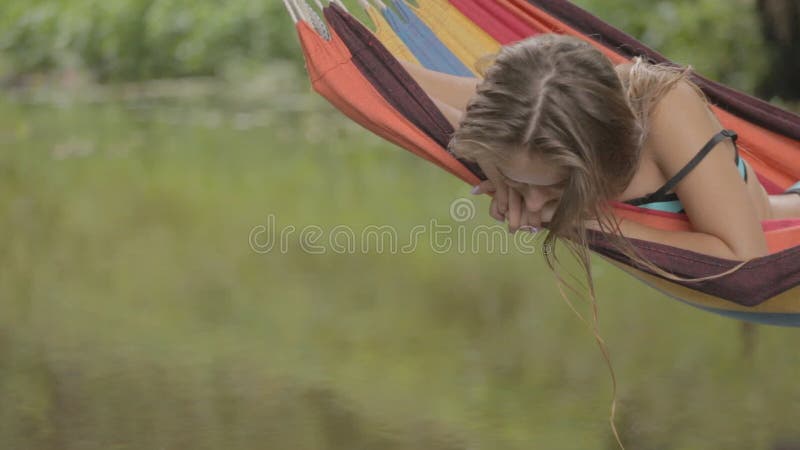 Bella guida della ragazza in un'amaca sopra l'acqua