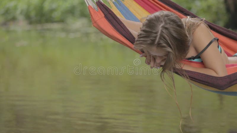 Bella guida della ragazza in un'amaca sopra l'acqua