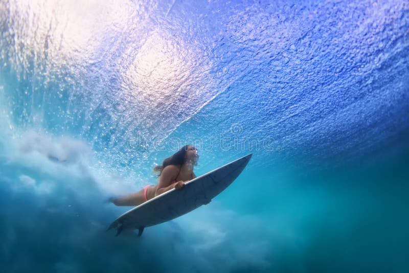 Bella immersione subacquea della ragazza del surfista sotto l'acqua con il bordo di spuma