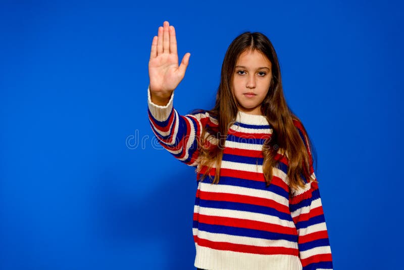 Bella ispanica che si è fermata con il palmo della mano isolata in uno studio blu. Una bella ispanica che fa il gesto di fermarsi con il palmo della mano isolata su uno sfondo blu di studio affronta con determinazione e coraggio i possibili pericoli che potrebbe affrontare