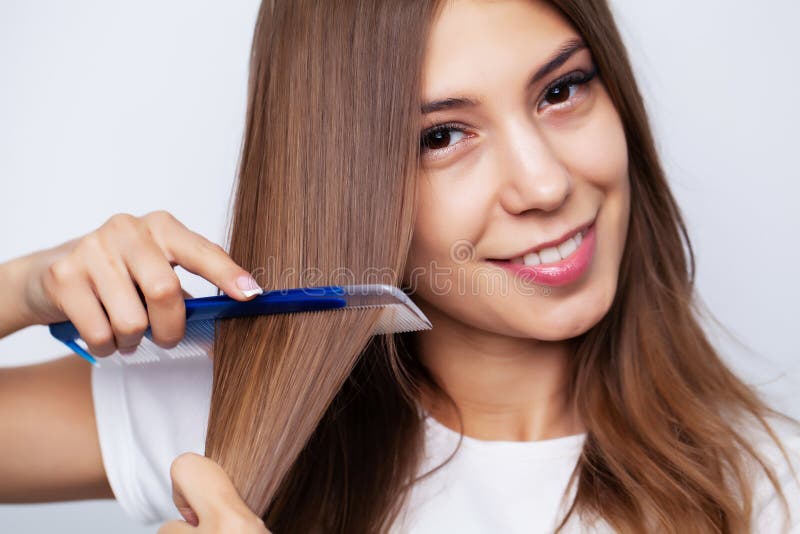 Beautiful young woman takes care of her hair, combing long hair with a comb. Beautiful young woman takes care of her hair, combing long hair with a comb.