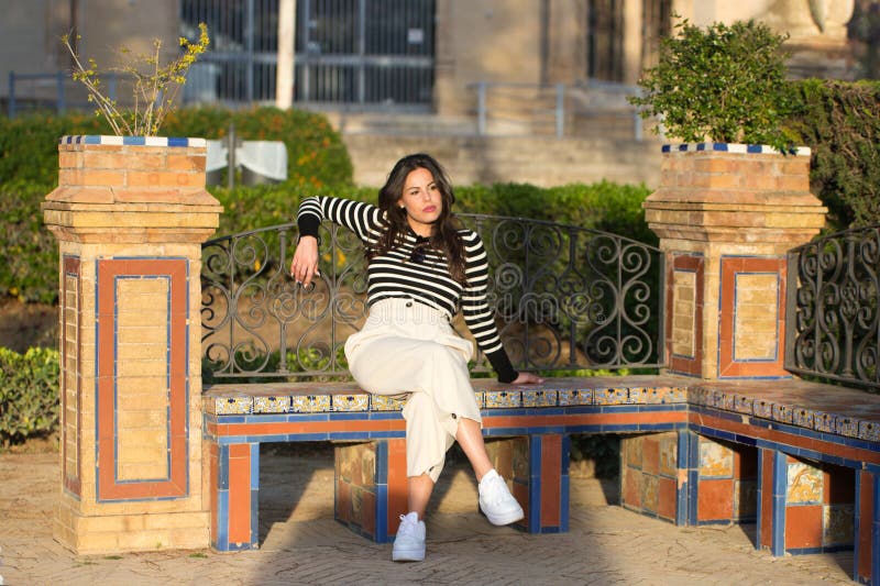 Bella joven de cabello largo y marrón sentada en un banco del parque. la mujer es seria y enojada. concepto de depresión imágenes de archivo libres de regalías