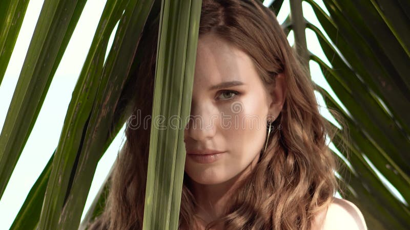 Bella joven posando con hojas de palma