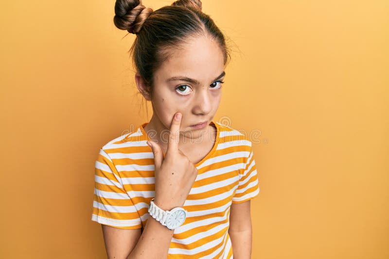 Bella morena pequeña niña con una camiseta casual a rayas apuntando al ojo observando tu gesto expresión sospechosa