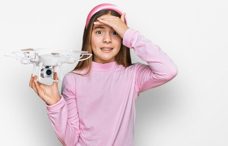 Bella morena pequeña niña usando drones estresada y frustrada con la cabeza en la cabeza sorprendida y furiosa cara foto de archivo libre de regalías