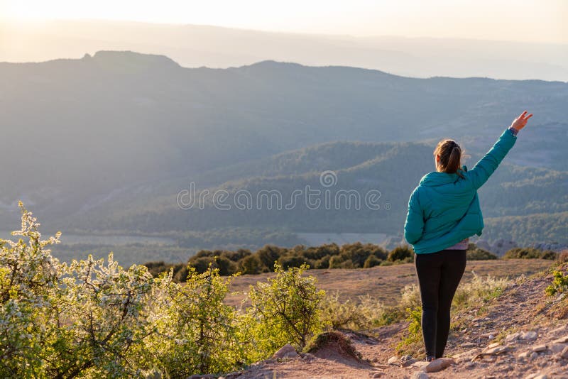 Bella mujer caminando por un camino al atardecer una mano arriba fotos de archivo libres de regalías