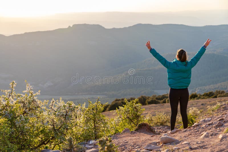 Bella mujer caminando por un sendero durante la puesta de sol manos arriba imágenes de archivo libres de regalías