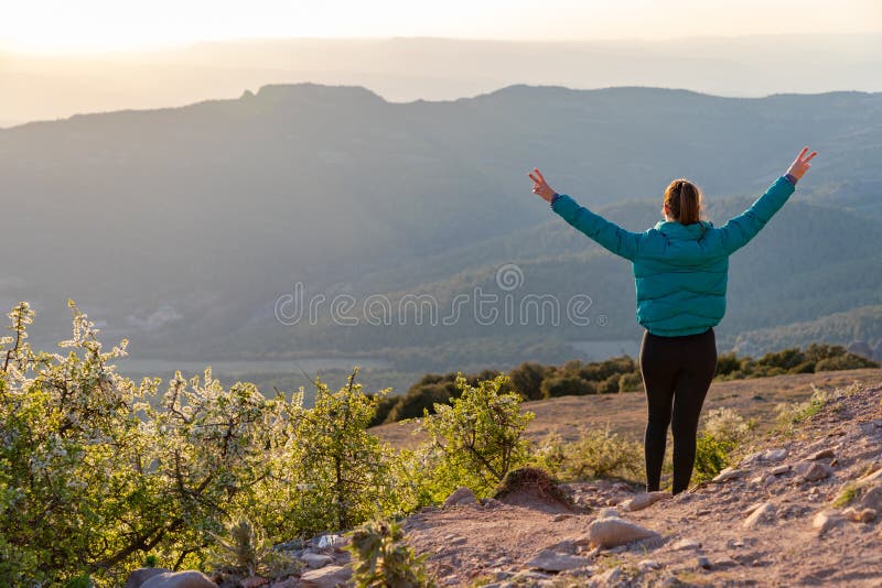Bella mujer caminando por un sendero durante la puesta de sol manos arriba fotos de archivo