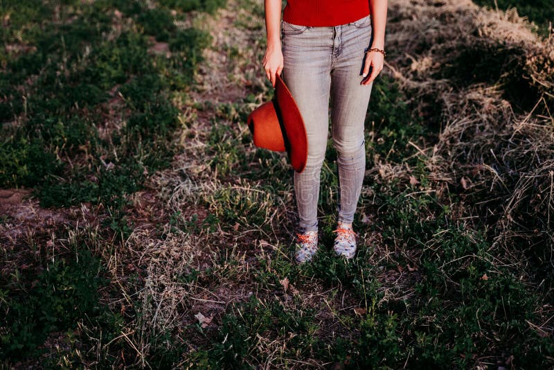 Bella mujer caucÃ¡sica sosteniendo un sombrero marrÃ³n al atardecer en el campo. Aire libre de la forma de vida. Ci? rrese encima d imágenes de archivo libres de regalías