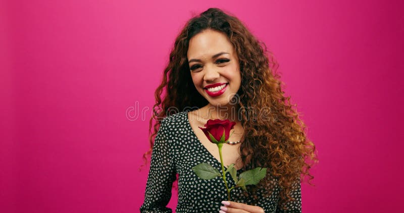Bella mujer multiétnica huele rosa rojo riéndose y sonriendo estudio rosa