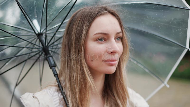 Bella mujer sosteniendo un paraguas transparente en el día de la lluvia